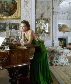 a woman in a green dress sitting at a piano