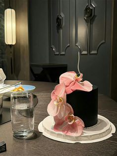 a fancy black and white cake with pink flowers on it sitting on top of a table