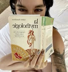 a woman laying on top of a bed holding a book in front of her face