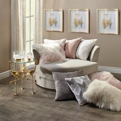 a living room filled with furniture and pillows on top of a wooden floor next to a window