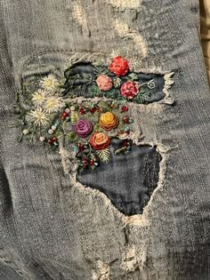 an old pair of jeans with flowers on the side and holes in the back pocket