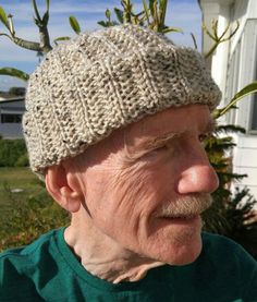 an older man wearing a knitted hat in front of a house