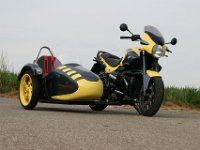 a yellow and black motorcycle parked on the side of the road next to some grass