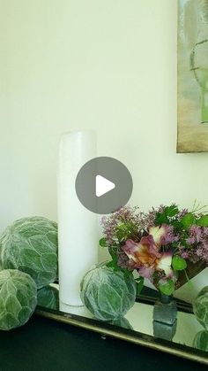 there is a vase with flowers on top of a table next to cabbages and other plants