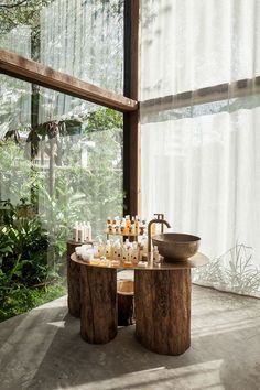 a table with candles and bottles on it in front of large windows that look out onto the outdoors