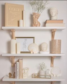 three white shelves filled with books and vases