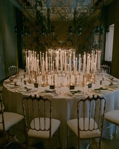 the table is set with many candles and place settings for dinner guests to sit at