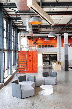 an office with orange walls and grey chairs in the center, surrounded by large windows