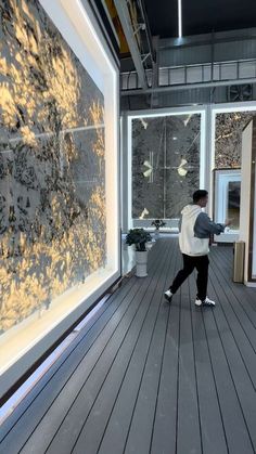 a man walking down a wooden floor next to a window