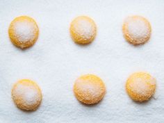 six powdered sugar balls are arranged in the shape of circles on a white surface