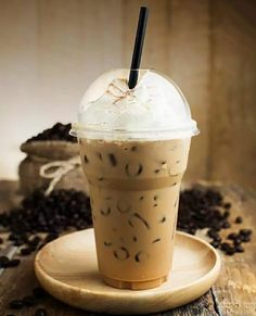 an iced coffee with whipped cream and chocolate sprinkles on a wooden plate