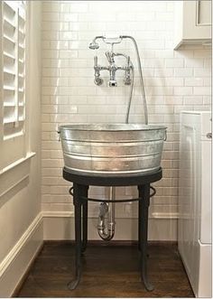 an old fashioned sink in the corner of a room with white brick walls and wood floors