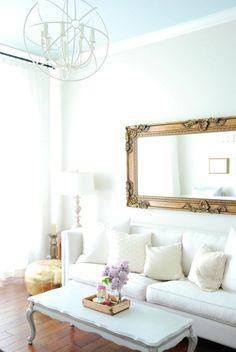 a living room filled with furniture and a large mirror on the wall above it's coffee table