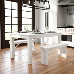 a white table and bench in a room with wooden floors, windows, and cabinets