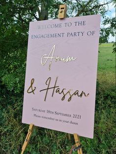 a welcome sign for the engagement party of aaron and jassan, in front of some trees