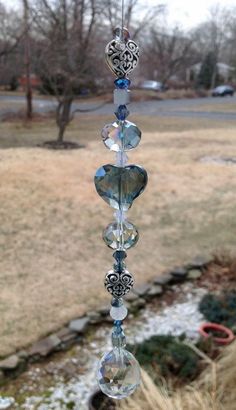 a wind chime hanging from the side of a window in front of a yard