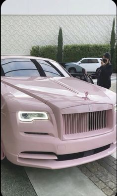 a pink rolls royce parked in front of a building