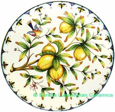 an artistically painted plate with fruit and leaves on the bottom, surrounded by butterflies