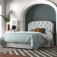 a white bed sitting next to a window on top of a hard wood floor in a bedroom