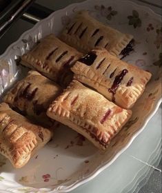 several pastries are on a plate with some sauce in the middle and one has been cut into small pieces