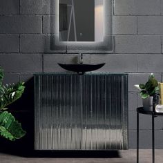 a bathroom with a sink, mirror and plant on the side table in front of it