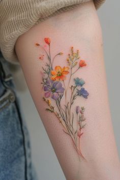 a close up of a person's arm with flowers tattooed on the side of it