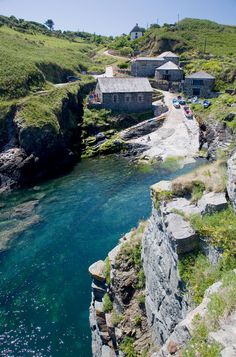 an aerial view of a small village on the side of a cliff with blue water