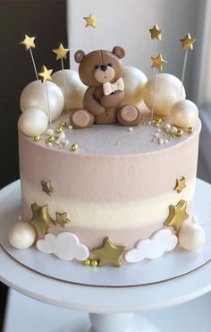 a teddy bear sitting on top of a pink and white cake with gold stars around it