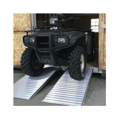 an atv is parked on the ramp in front of a building with its doors open