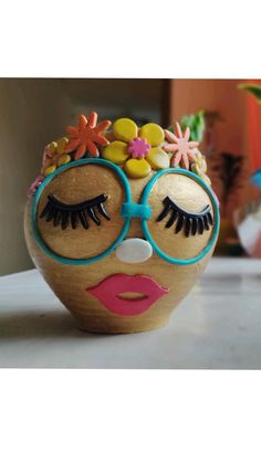 a close up of a ceramic face with eye glasses and flowers on it's head