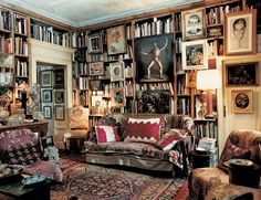 a living room filled with lots of furniture and bookshelves full of pictures on the wall