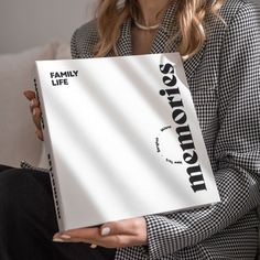 a woman holding up a book with the words family life written on it in black and white