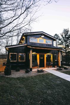 a small black house sitting on top of a lush green field