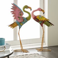 two flamingos standing next to each other on a rug in front of a window