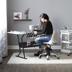 a woman sitting at a desk using a sewing machine