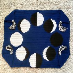 a blue purse with white and black circles on the front is laying on a carpet