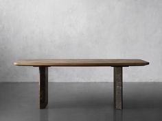 a wooden table sitting on top of a floor next to a white wall and cement walls