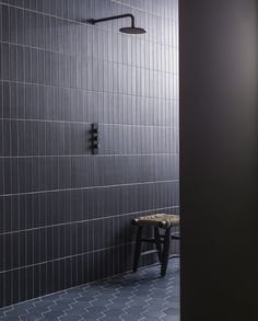 a black and white tiled bathroom with a bench in the corner, next to a shower head