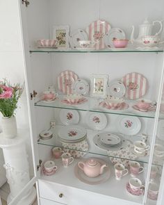 a china cabinet filled with pink and white dishes