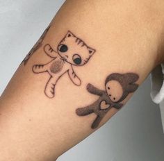 a person with a cat tattoo on their arm holding a teddy bear in the other hand