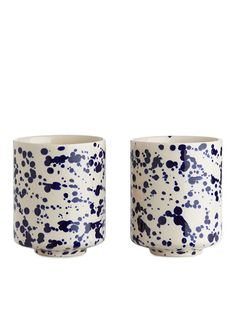 two blue and white cups sitting next to each other on a white surface with black dots