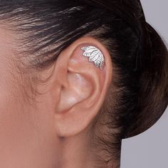 a woman's ear with a leaf tattoo on it