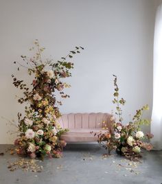 a pink couch sitting next to flowers on top of a floor