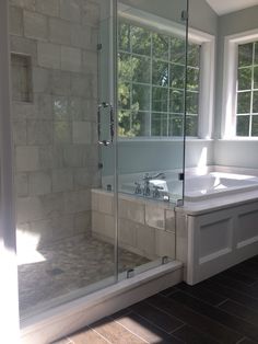 a bathroom with a walk in shower next to a bathtub and sink under a window