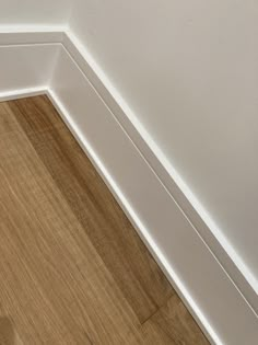 the corner of a room with white walls and wood flooring is painted in an off - white color