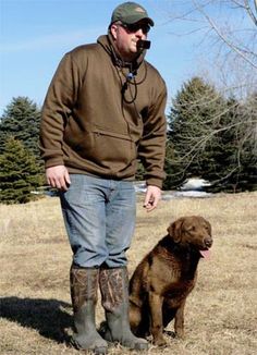 a man standing next to a brown dog in a field