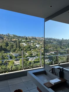 a bathroom with a large window overlooking the city and hills in the backround