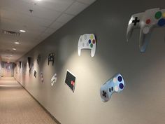 several video game controllers mounted to the side of a wall in an office hallway with carpeted flooring