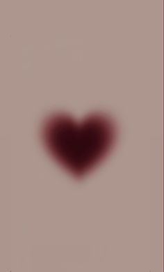 a blurry image of a red heart in the middle of a gray background with black spots