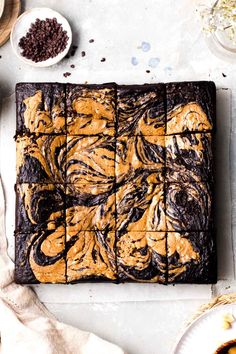 chocolate brownies with peanut butter frosting on a cutting board next to bowls of cookies